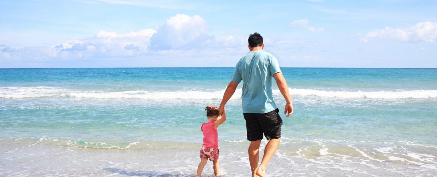 Father walking his young daughter into the waves