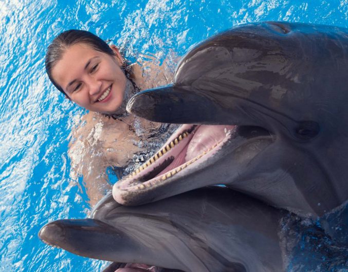 Woman swimming with dolphin who is smiling in the water
