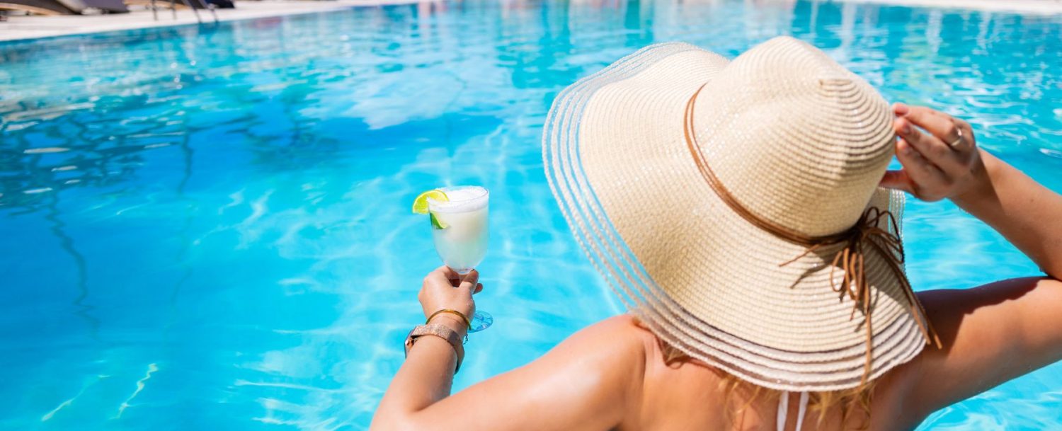 woman in hat in Florida pool with a drink